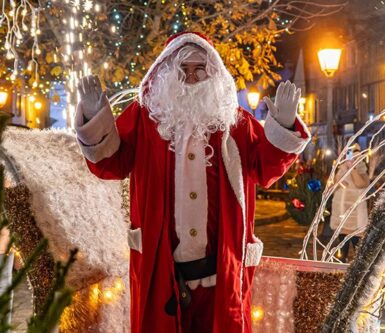 une image du père Noël devant le village de noël illuminé