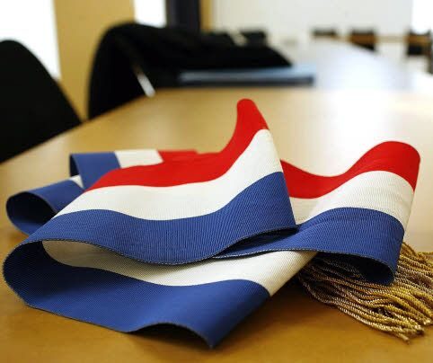 Écharpe tricolore à pompons dorés posée sur une table que le Maire ou les élus peuvent porté