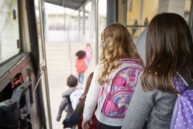 Des enfants avec des sacs sur le dos descendent du bus scolaire