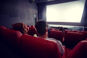 Vue d'un écran de cinéma depuis le haut de la salle, derrière les sièges