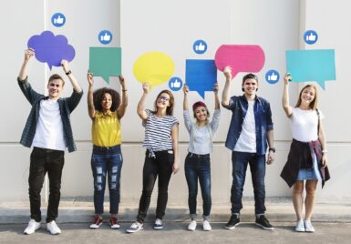 Un groupe de jeunes tient à bout de bras des bulles de dialogue colorées, et des 