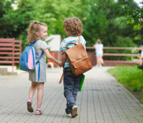 deux jeunes enfants portant des cartables et se tenant la main