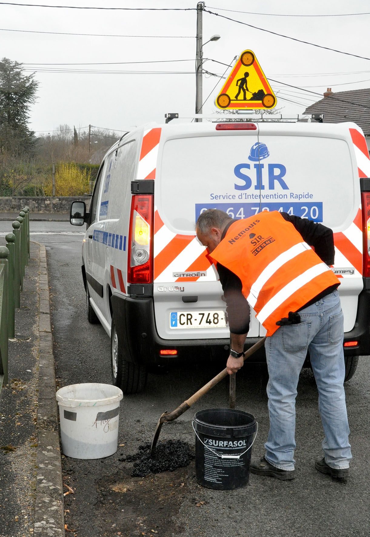 Un technicien du Service d'Intervention Rapide intervient pour reboucher un trou sur la chaussée à Nemours