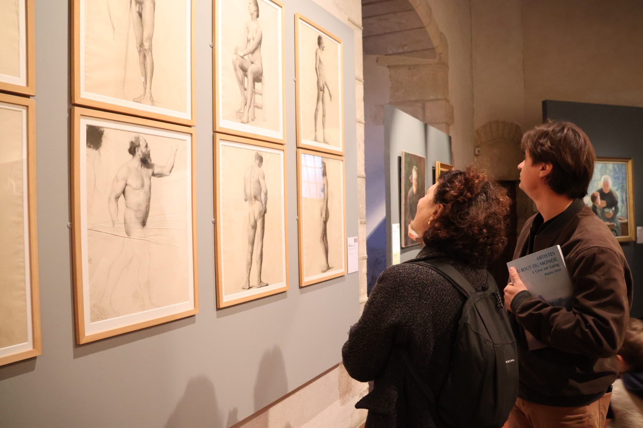 Deux personnes admirent des dessins de nu académique à l'intérieur du château-musée de Nemours