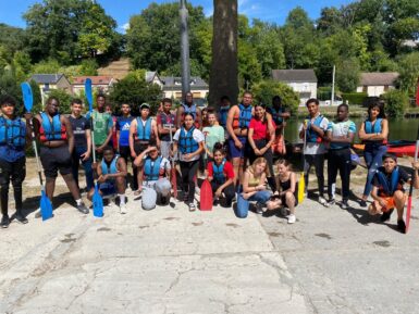 Un groupe d'adolescents sur les bords du Loing, portant de gilets de sauvetage et tenant des rames, en vue d'une activité type kayak