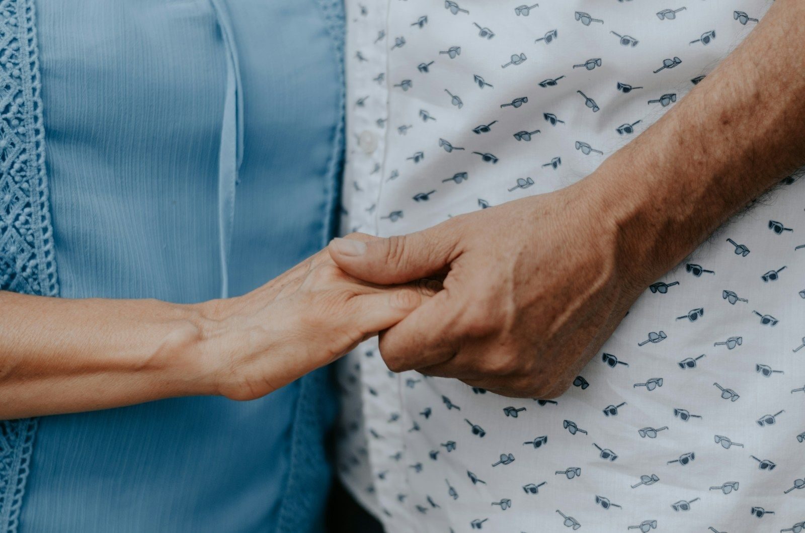 Deux personnes se tenant la main, dont une marquée par l'âge