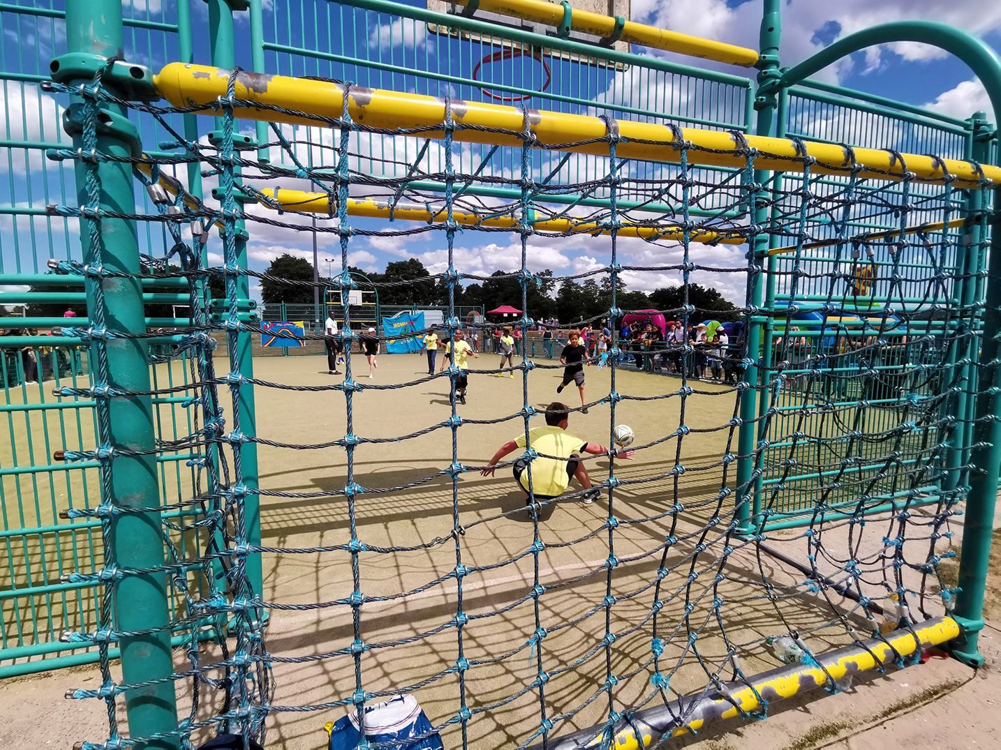 des enfants jouant au foot, vus de derrière les buts, sur le terrain d'aventure de nemours