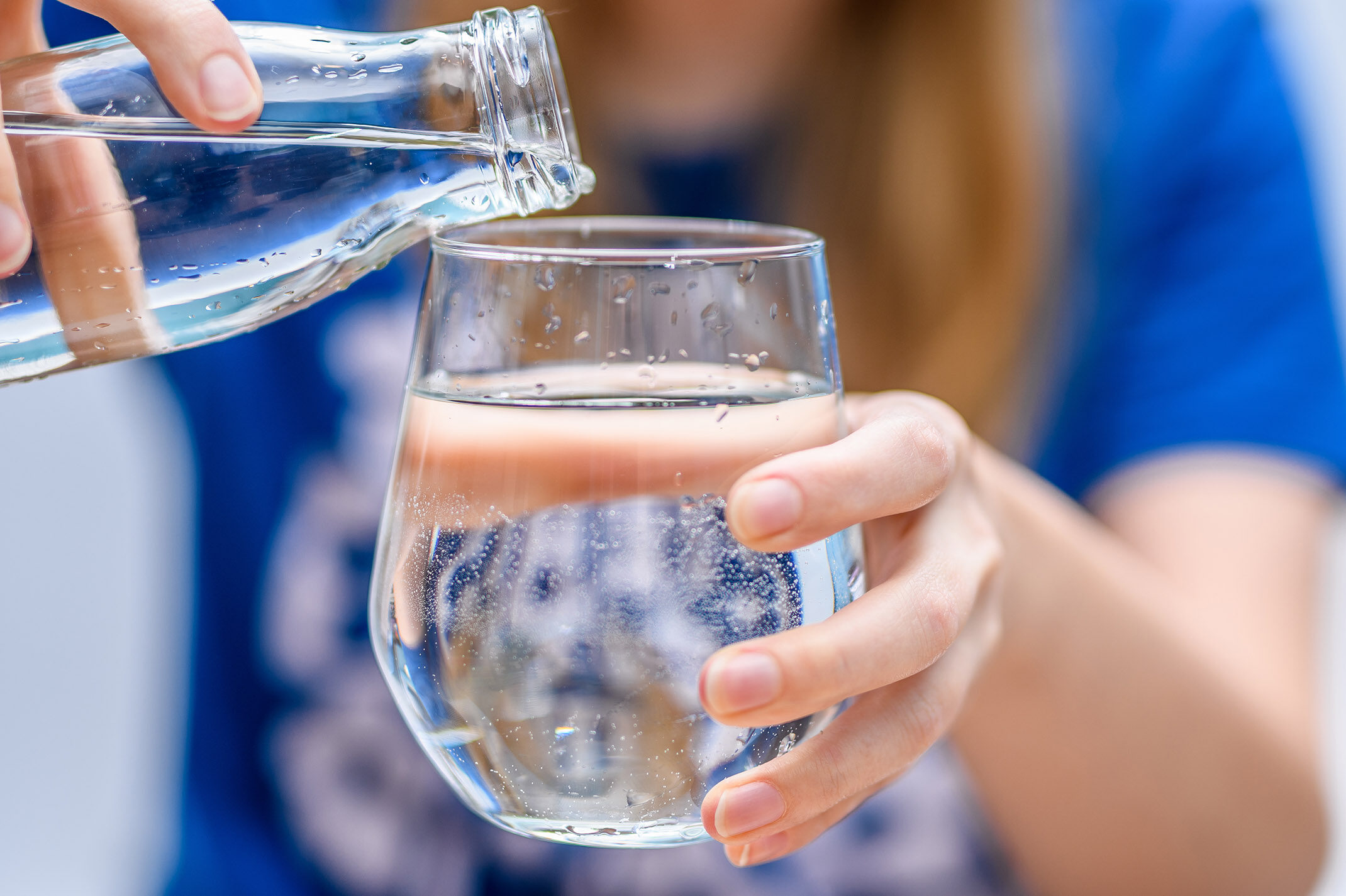 Une personnes ce serre de l'eau dans un verre