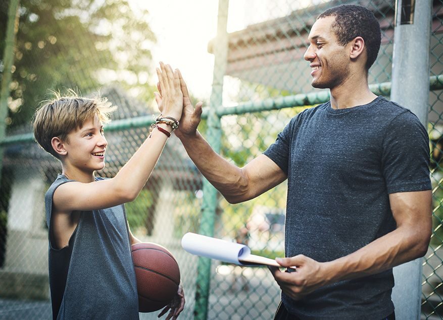 un jeune garçon tenant un ballon de basket et un adulte se topent dans la main