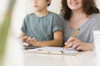 un enfant et une adulte prennent des notes tout en consultant un site internet - crédit photo : freepik