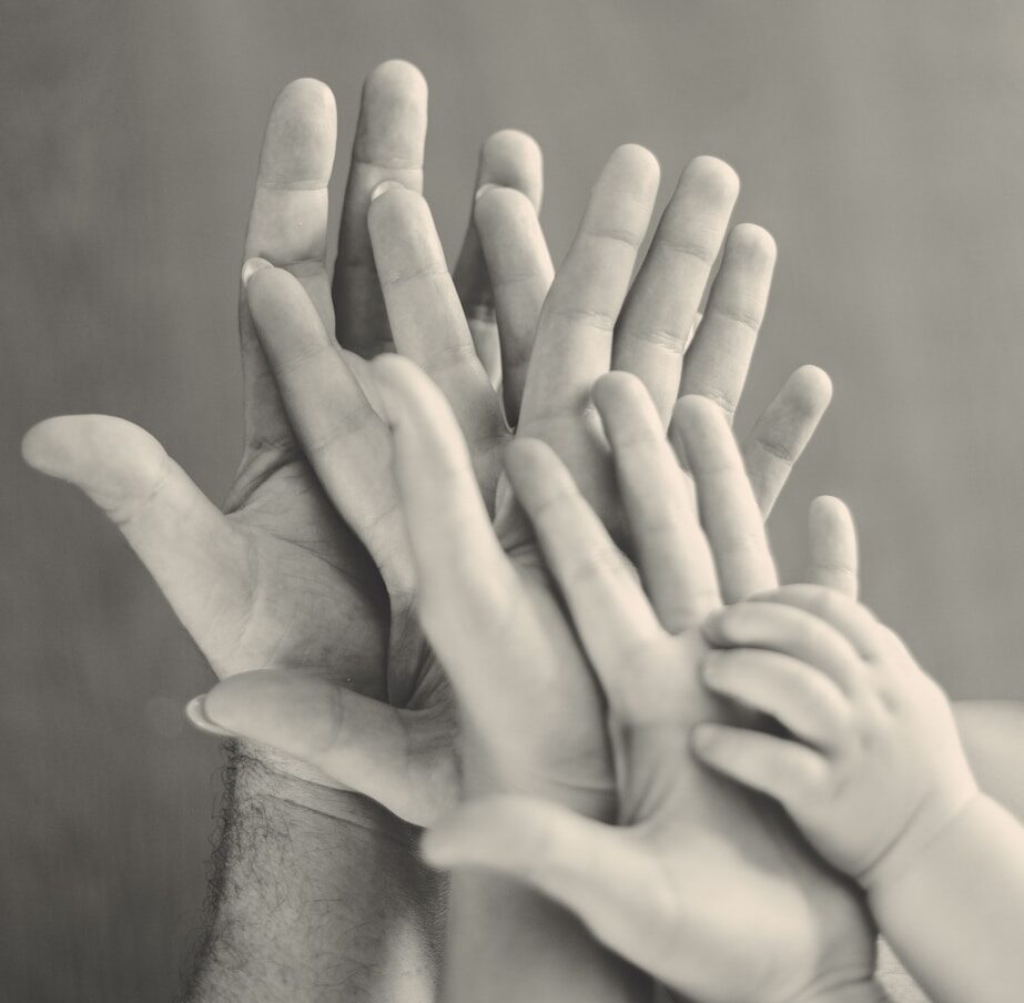 grayscale photo of family's hands